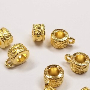 May include: Gold-toned metal bead caps with an ornate design. The bead caps have a small loop on one side.