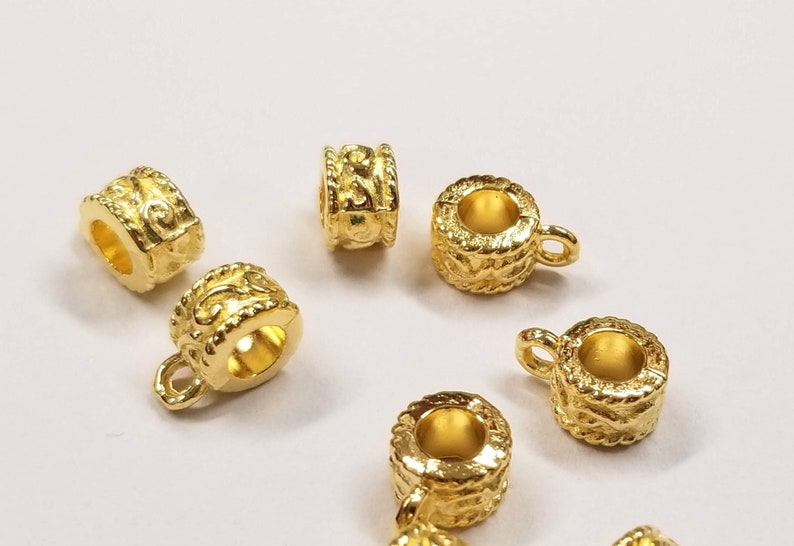 May include: Gold-toned metal bead caps with an ornate design. The bead caps have a small loop on one side.