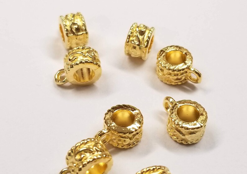 May include: Gold-toned metal bead caps with a decorative design. The bead caps have a small loop on one side for attaching to a necklace or bracelet.
