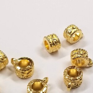 May include: Eight gold-toned metal bead caps with an ornate design. The bead caps have a hole in the center and are designed to be used as a decorative accent for jewelry making.