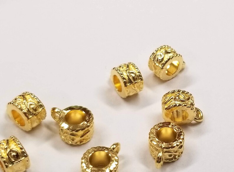 May include: Eight gold-toned metal bead caps with an ornate design. The bead caps have a hole in the center and are designed to be used as a decorative accent for jewelry making.