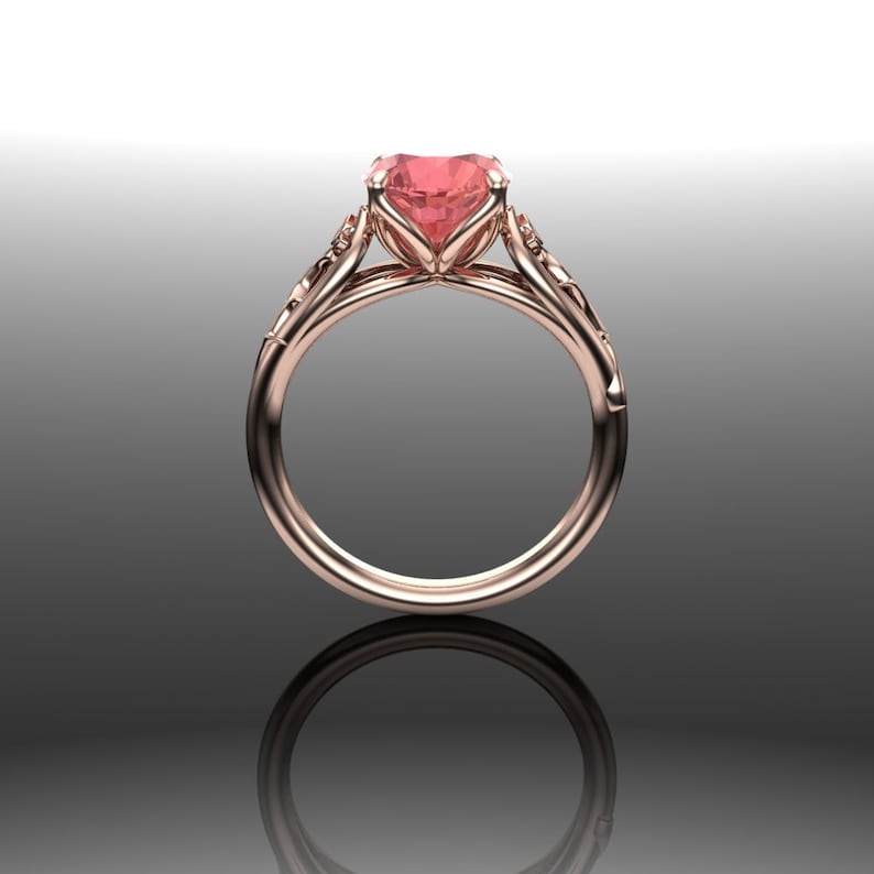 Puede incluir: Un anillo de compromiso de oro rosa con una piedra preciosa rosa en forma de coraz&oacute;n y detalles florales intrincados.