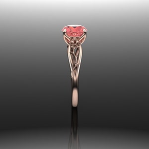 Puede incluir: Un anillo de compromiso de oro rosa con una piedra preciosa rosa engastada en un dise&ntilde;o floral.