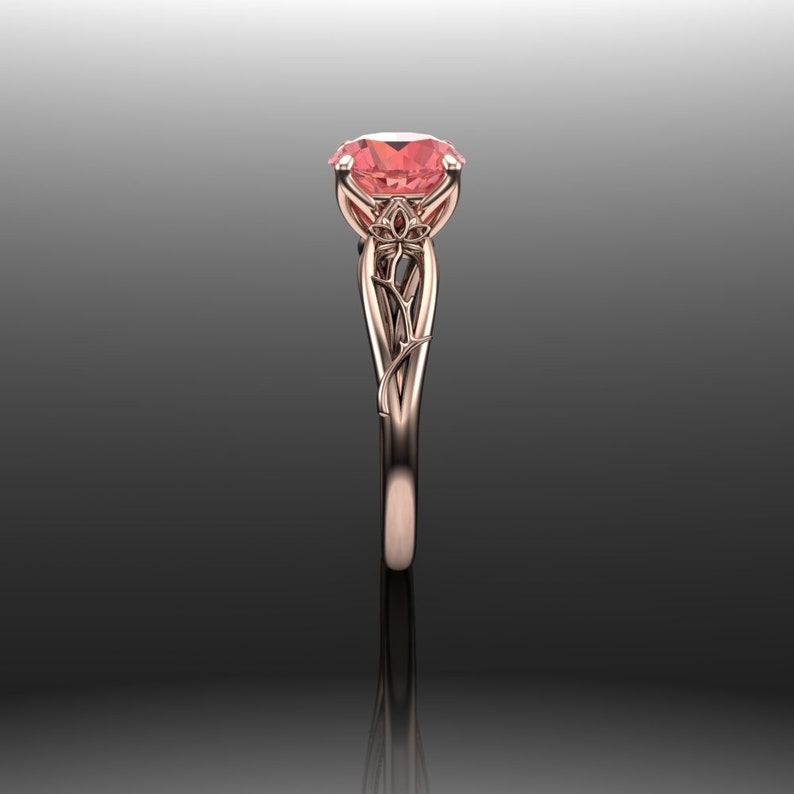 Puede incluir: Un anillo de compromiso de oro rosa con una piedra preciosa rosa engastada en un dise&ntilde;o floral.