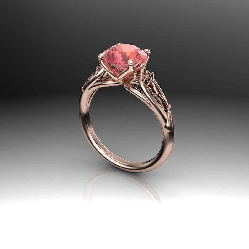 Puede incluir: Un anillo de compromiso de oro rosa con un delicado dise&ntilde;o floral y una piedra preciosa rosa en el centro.