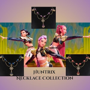 May include: The image showcases the "Huntrix Necklace Collection." The necklaces feature gold chains, pearl accents, and a central pendant with a teardrop-shaped gemstone. The background includes animated figures in performance attire.