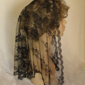 May include: Black lace veil with a scalloped edge. The veil is sheer and delicate, with a floral pattern.