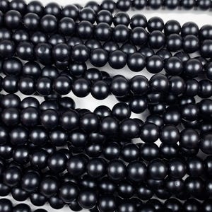 May include: A strand of black matte round beads. The beads are smooth and have a uniform size and shape.