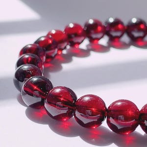 Puede incluir: Un brazalete de piedras preciosas rojas con cuentas redondas. El brazalete est&aacute; hecho de piedras naturales y es una hermosa joya.