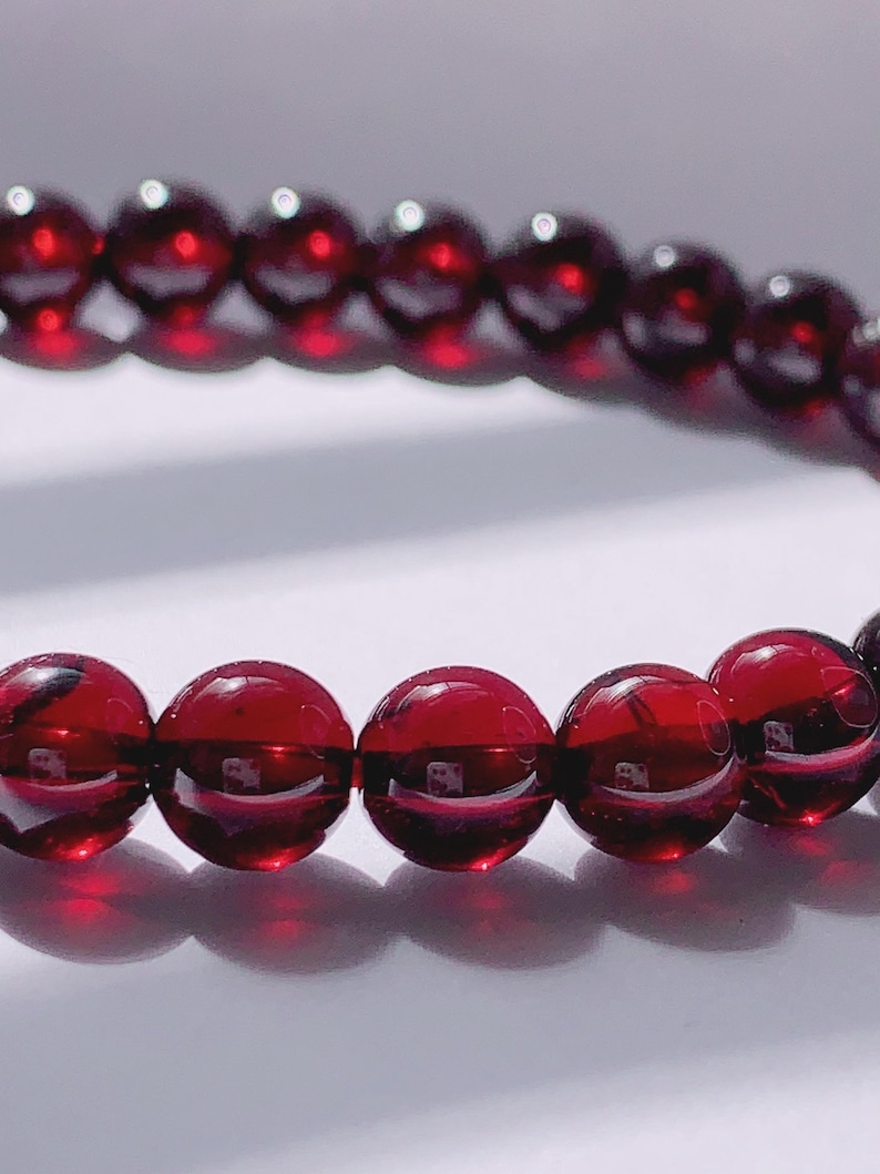 Puede incluir: Un brazalete de piedras preciosas rojas con cuentas redondas. El brazalete est&aacute; hecho de piedras naturales y tiene un acabado pulido.