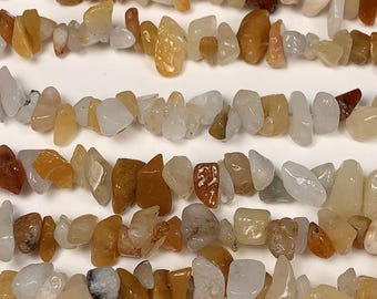 May include: A strand of chip-shaped natural gemstone beads in shades of white, yellow, and orange. The beads are irregular in shape and size, and they have a smooth, polished finish.