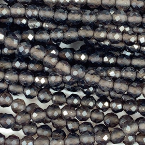 May include: A strand of dark gray faceted gemstone beads. The beads are round and have a smooth, polished finish.