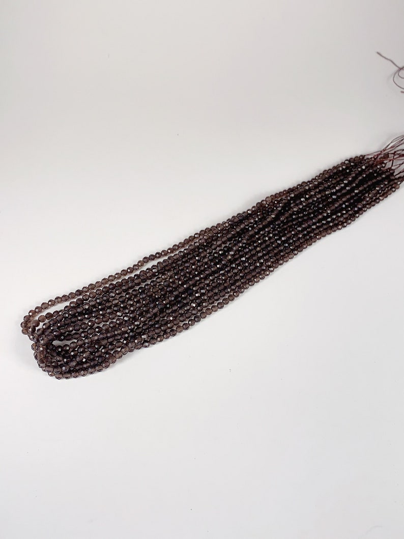 May include: A strand of dark brown faceted gemstone beads. The beads are strung on a thin thread and are ready to be used for jewelry making.