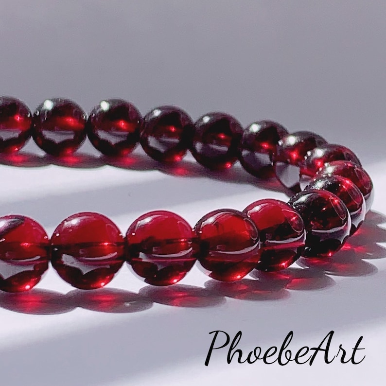 Puede incluir: Un brazalete de piedras preciosas rojas hecho de cuentas redondas. El brazalete est&aacute; hecho de piedras de granate naturales.