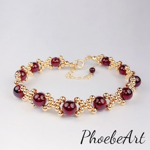 May include: A gold bracelet with red gemstone beads. The bracelet has a delicate chain clasp.