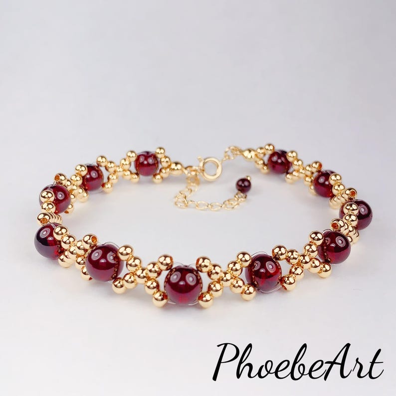 May include: A gold bracelet with red gemstone beads. The bracelet has a delicate chain clasp.