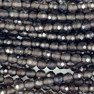 May include: A strand of dark gray faceted glass beads. The beads are round and have a smooth, polished finish.
