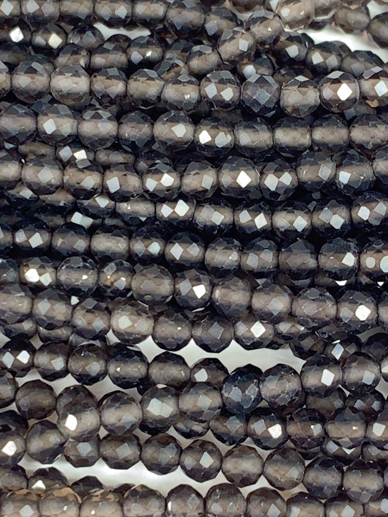 May include: A strand of dark gray faceted glass beads. The beads are round and have a smooth, polished finish.