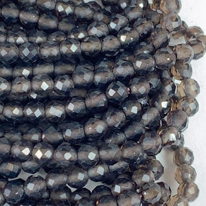 May include: A strand of dark gray faceted gemstone beads. The beads are round and have a smooth, polished finish.