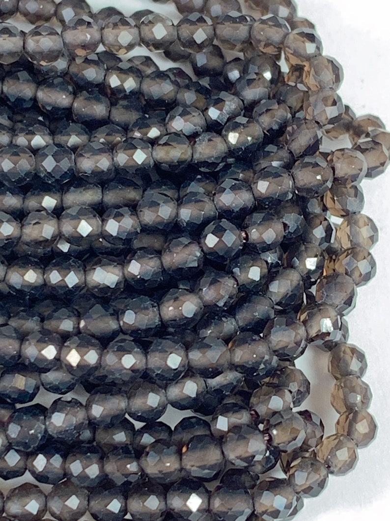 May include: A strand of dark gray faceted gemstone beads. The beads are round and have a smooth, polished finish.
