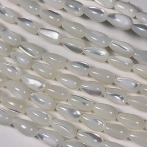 May include: Rows of luminous, pearlescent teardrop-shaped beads. The beads have a smooth, glossy surface with subtle variations in color, reflecting light. These beads are ideal for jewelry making, such as necklaces and earrings.