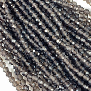 May include: A strand of dark gray faceted gemstone beads. The beads are round and have a smooth, polished finish.