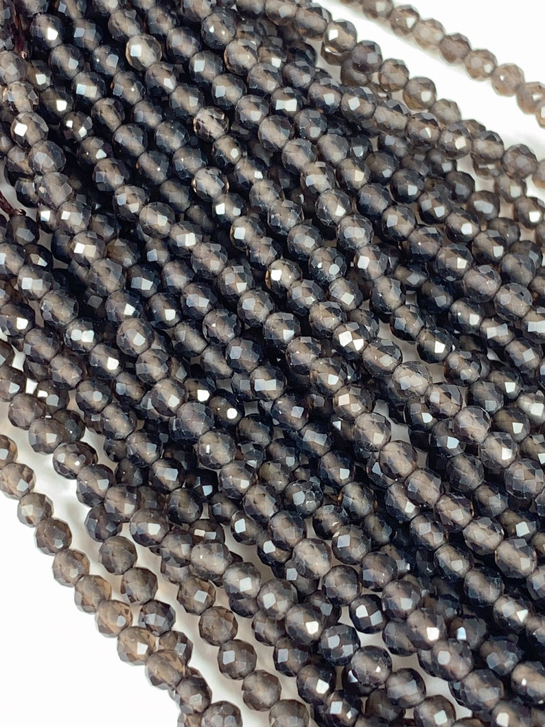 May include: A strand of dark gray faceted gemstone beads. The beads are round and have a smooth, polished finish.