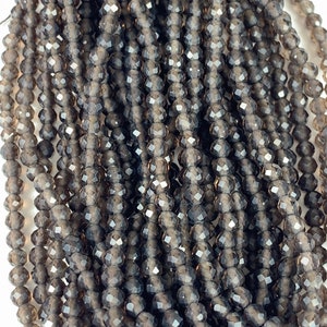 May include: A strand of smoky quartz faceted beads. The beads are a dark gray color with a slight shimmer. They are approximately 4mm in size.