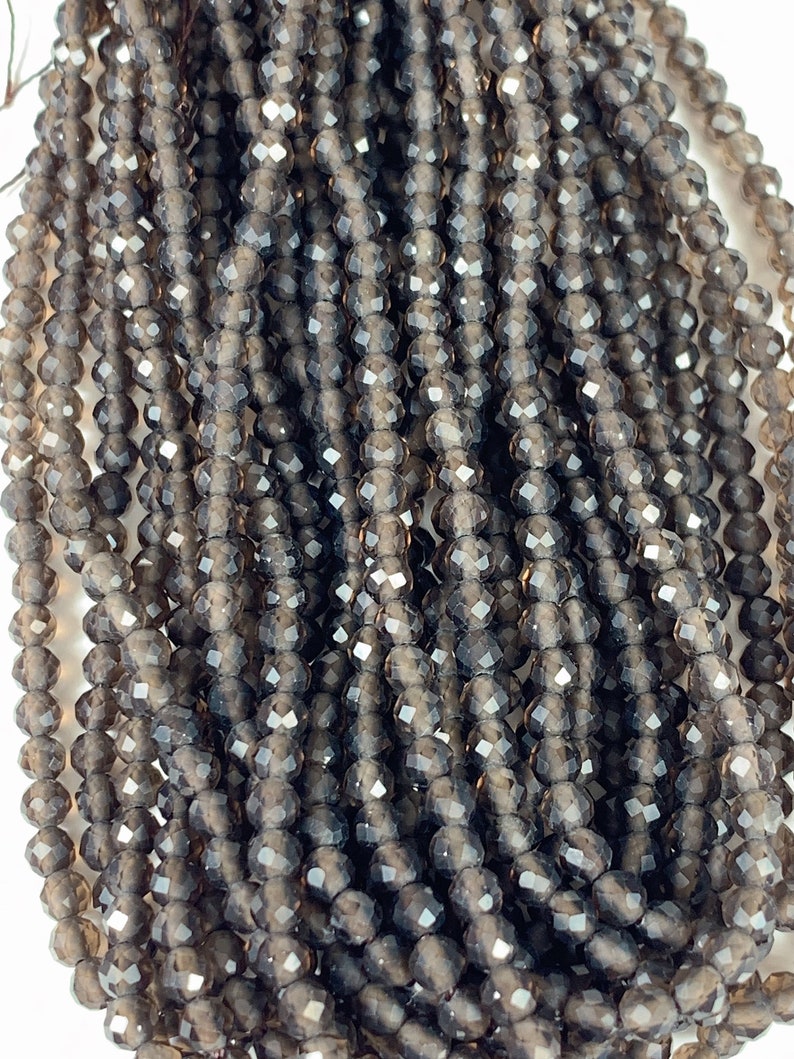 May include: A strand of smoky quartz faceted beads. The beads are a dark gray color with a slight shimmer. They are approximately 4mm in size.