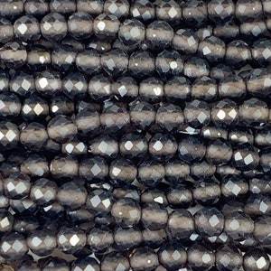 May include: A close-up of a strand of black faceted glass beads. The beads are round and have a smooth, polished finish.