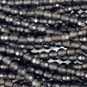 May include: A strand of black faceted glass beads. The beads are round and have a smooth, polished finish.