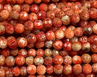 Puede incluir: Una hebra de cuentas de piedra preciosa facetadas de color naranja y blanco. Las cuentas son pequeñas y redondas, con una superficie texturizada.