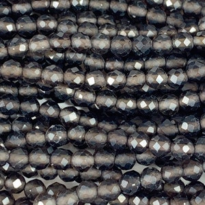 May include: A strand of dark gray faceted glass beads. The beads are round and have a smooth, polished finish.