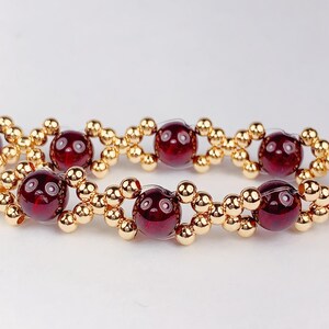 May include: A red gemstone bracelet with gold beads. The bracelet is made with round red gemstones and small gold beads.