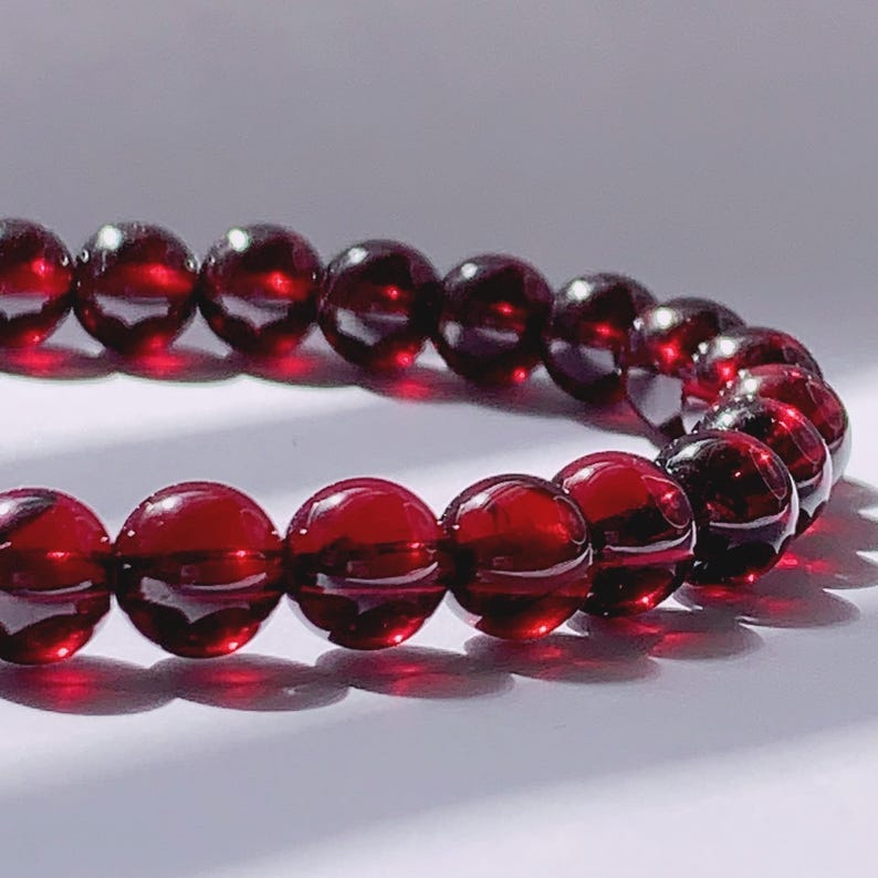 Puede incluir: Un brazalete de piedras preciosas rojas con cuentas redondas. El brazalete est&aacute; hecho de piedras de granate naturales.