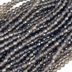 May include: A strand of dark gray faceted gemstone beads. The beads are round and have a smooth, polished finish.