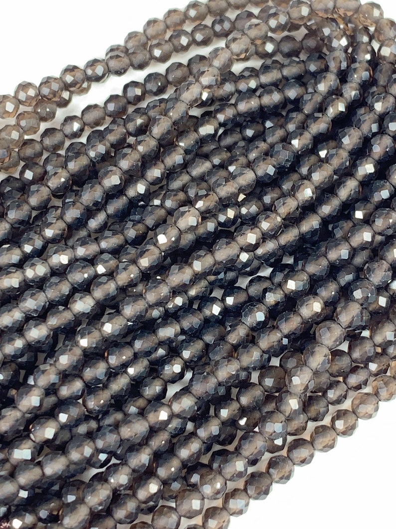 May include: A strand of dark gray faceted gemstone beads. The beads are round and have a smooth, polished finish.