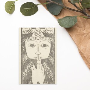 Peut inclure: Une illustration en noir et blanc d'une femme portant une couronne et une longue robe flottante. Son doigt est pressé sur ses lèvres, comme pour indiquer le silence.