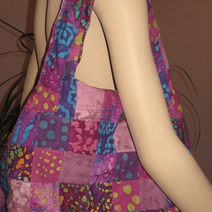 May include: A patchwork tote bag with a purple, pink, blue, and green floral pattern. The bag has a single strap and is made of fabric.