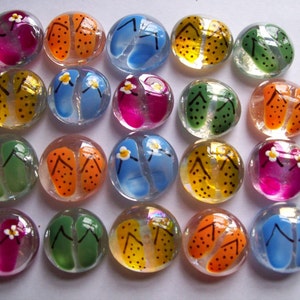 May include: A collection of 18 glass stones, each painted with a different design of flip flops. The flip flops are painted in various colors, including blue, green, orange, yellow, and pink.