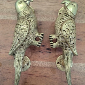May include: A pair of gold-toned parrot door handles. The handles are detailed with intricate carvings and have a realistic appearance.