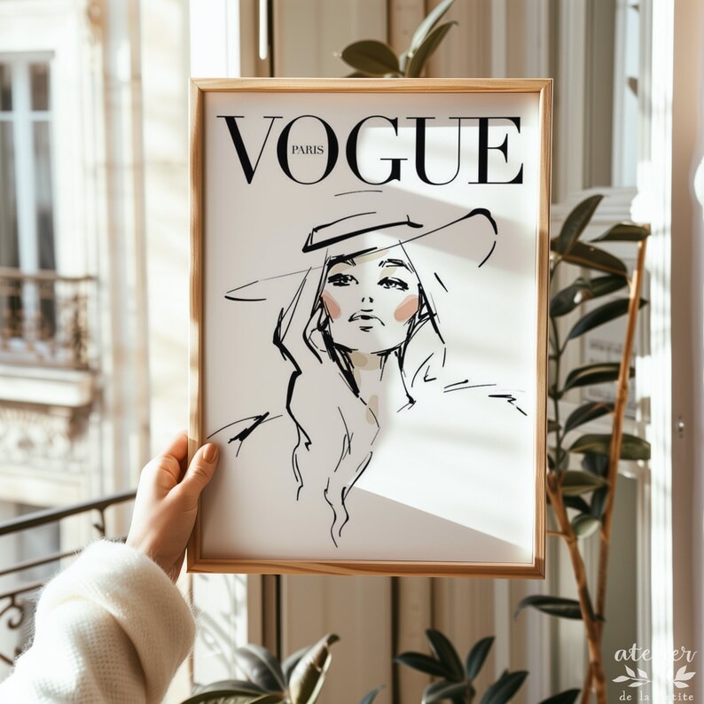 Pu&ograve; includere: Una stampa incorniciata di un'illustrazione in bianco e nero di una donna con un cappello. Il testo "VOGUE PARIS" &egrave; in cima alla stampa.