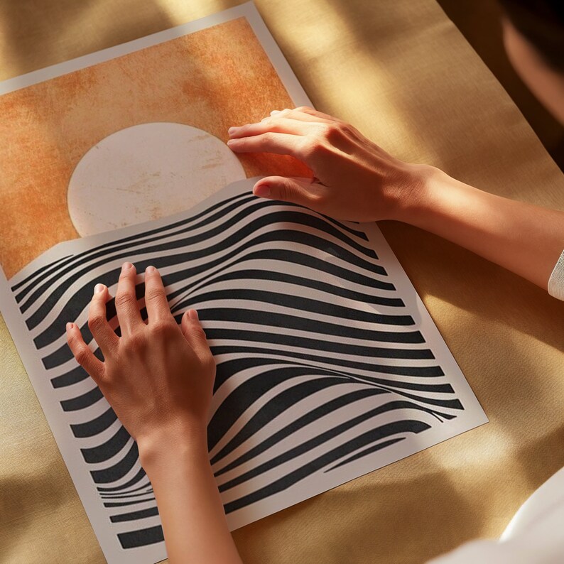 May include: A person is holding a black and white striped poster with a large white circle on a tan background. The poster has a wavy, optical illusion design.