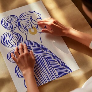 May include: A white background with a blue and white striped illustration of a woman with a gold earring. The woman's hair is styled in a bun with a blue and white striped design.