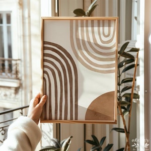 Pu&ograve; includere: Una stampa incorniciata con un design astratto con archi marroni e beige su uno sfondo bianco.