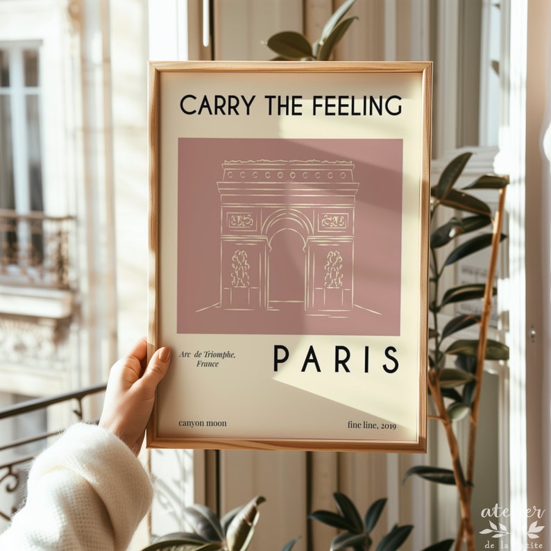 Pu&ograve; includere: Un poster minimalista con un disegno a linea dell'Arco di Trionfo a Parigi, Francia. Il poster ha uno sfondo rosa chiaro con il testo "Carry the Feeling" in nero in alto e "Paris" in nero in basso. Il testo "Arc de Triomphe, France" &egrave; in bianco sotto il disegno e "canyon moon" e "fine line, 2019" sono in bianco in basso.