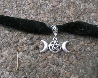 May include: A black velvet choker necklace with a silver pendant featuring a triple moon and pentagram charm.