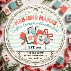 Puede incluir: Un letrero redondo con el texto Mahjong Mamas, Laughter, Friendship, and One More Hand!, EST. 2026, The Tile Squad y los nombres Sarah, Jessica, Emily, Maria y Chloe. El diseño incluye fichas de mahjong coloridas y una cinta roja.