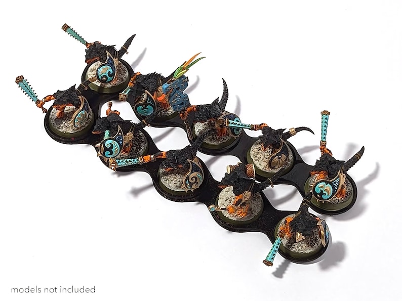 May include: A black plastic storage tray with eight circular compartments, each holding a miniature painted figure. The figures are black, blue, and gold, and are mounted on round bases.