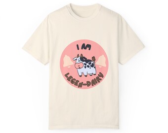 May include: A cream-colored t-shirt with a pink circle graphic featuring a cartoon cow and the text "I am legen-dairy".